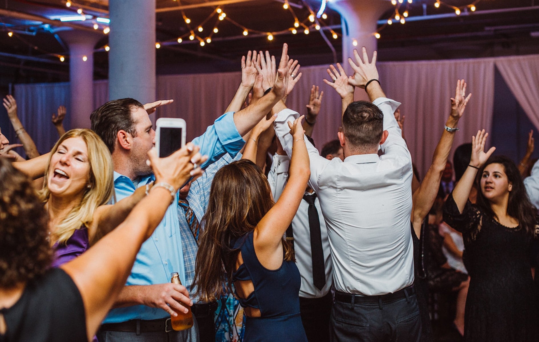 group of friends and guests throwing their hands in the air